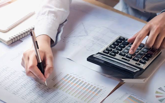 Accountant reconciling monthly statements with a calculator and printed reports